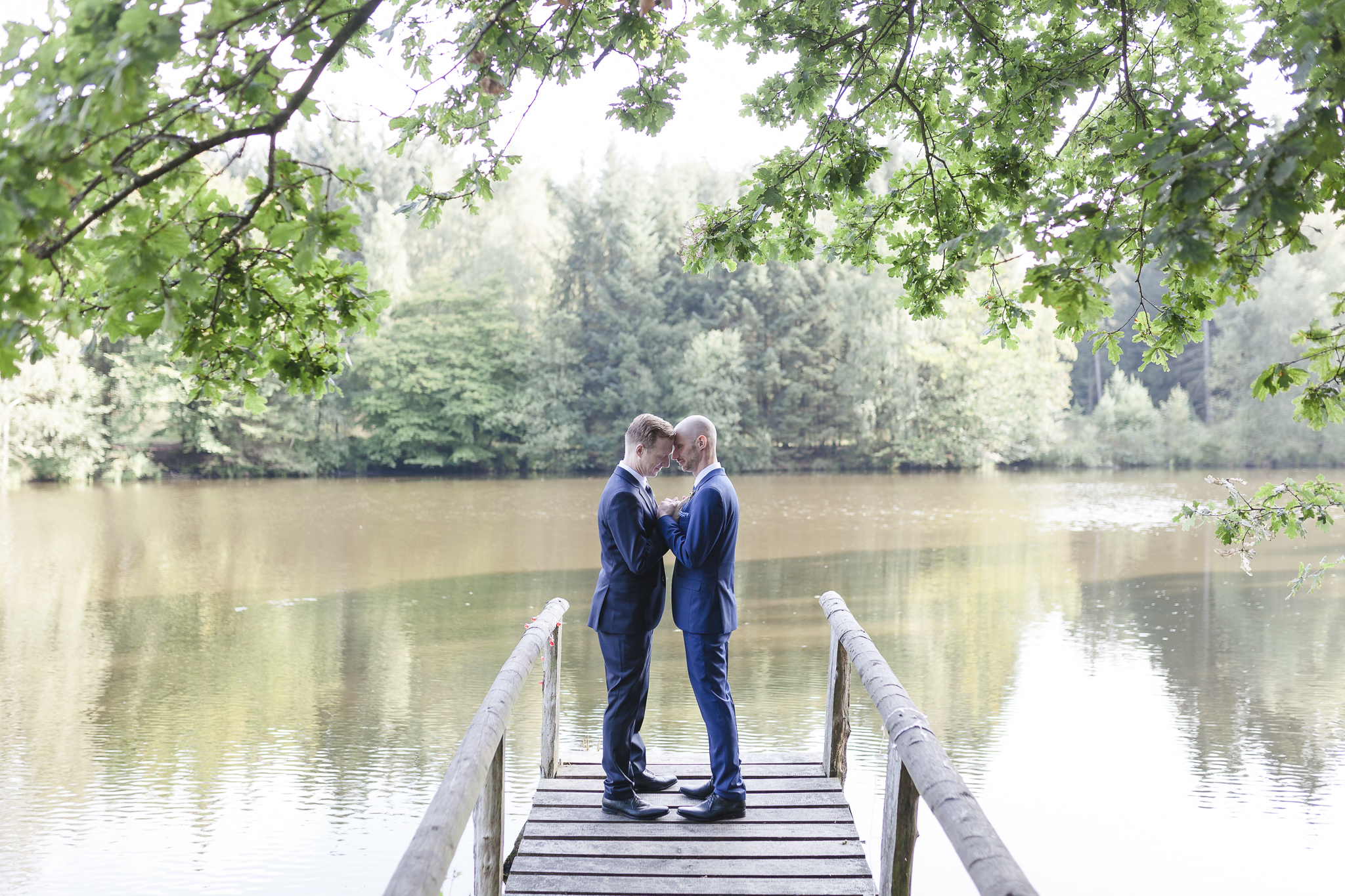 Hochzeitsfotograf Hamburg - schwules Brautpaar steht auf Steg am See
