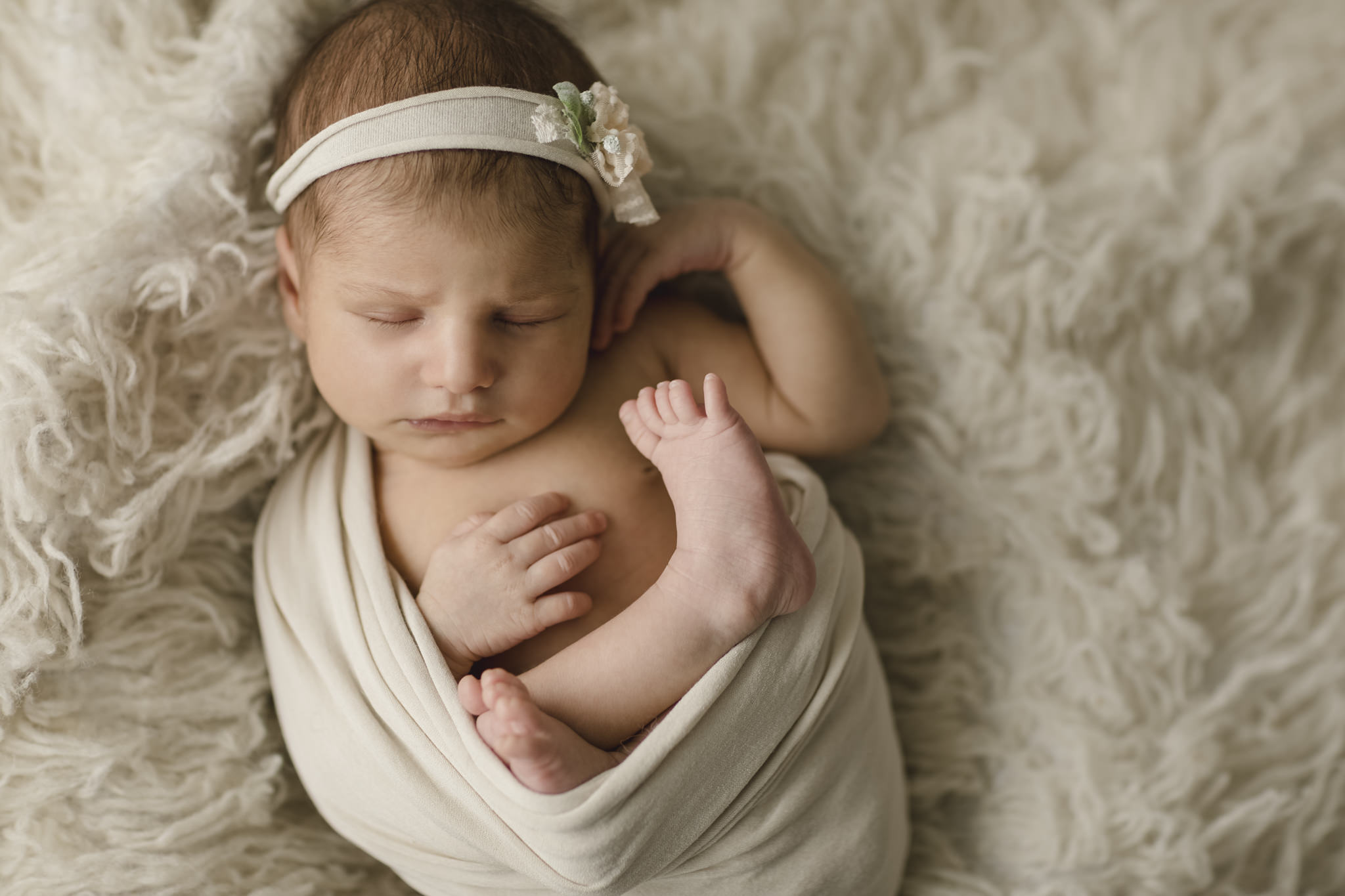 Newbornfotografie Workshop - Baby liegt eingewickelt auf einem kuscheligen Fell