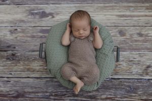 Babyfotograf Hamburg - Baby liegt auf grüner Decke in einem Körbchen