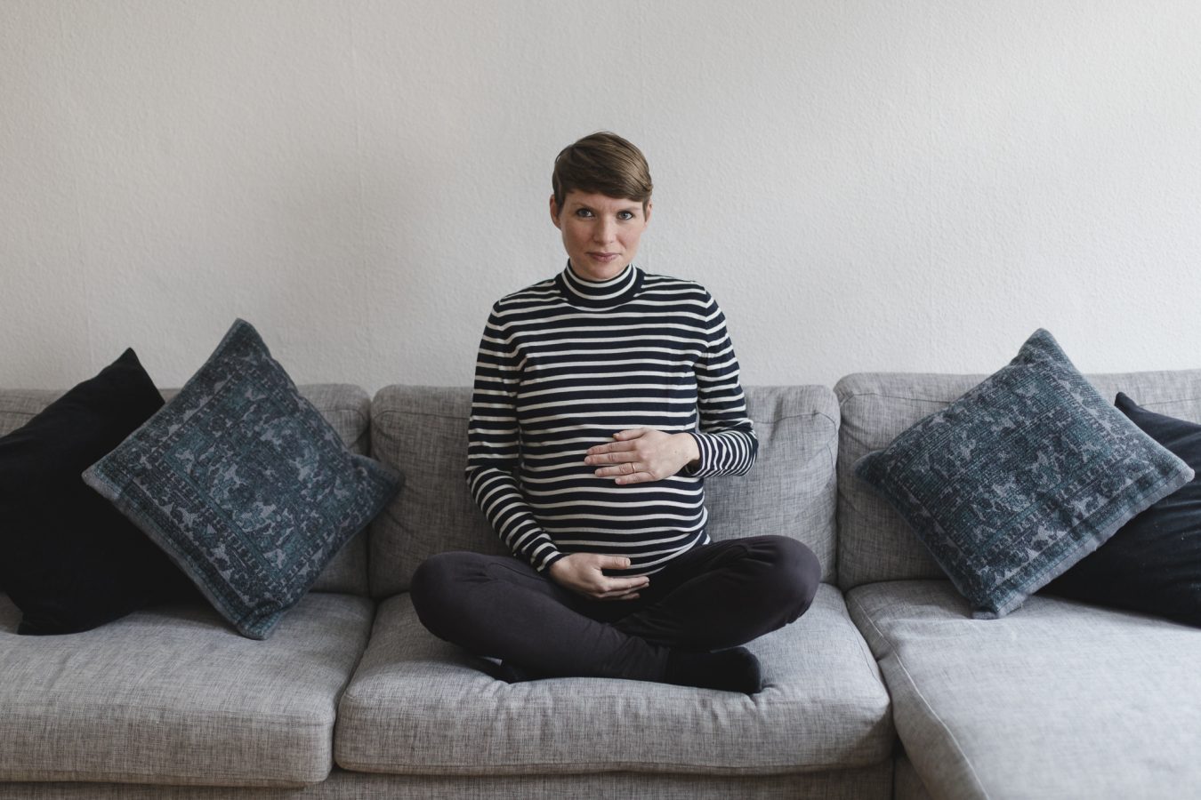 Babyfotograf Hamburg - Schangere sitzt im Schneidersitz auf dem Sofa
