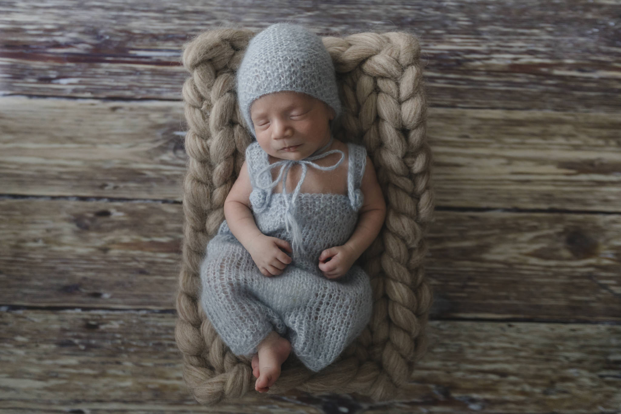 Babyfotograf Hamburg - Baby liegt in blauem Strampler im Körbchen und schläft