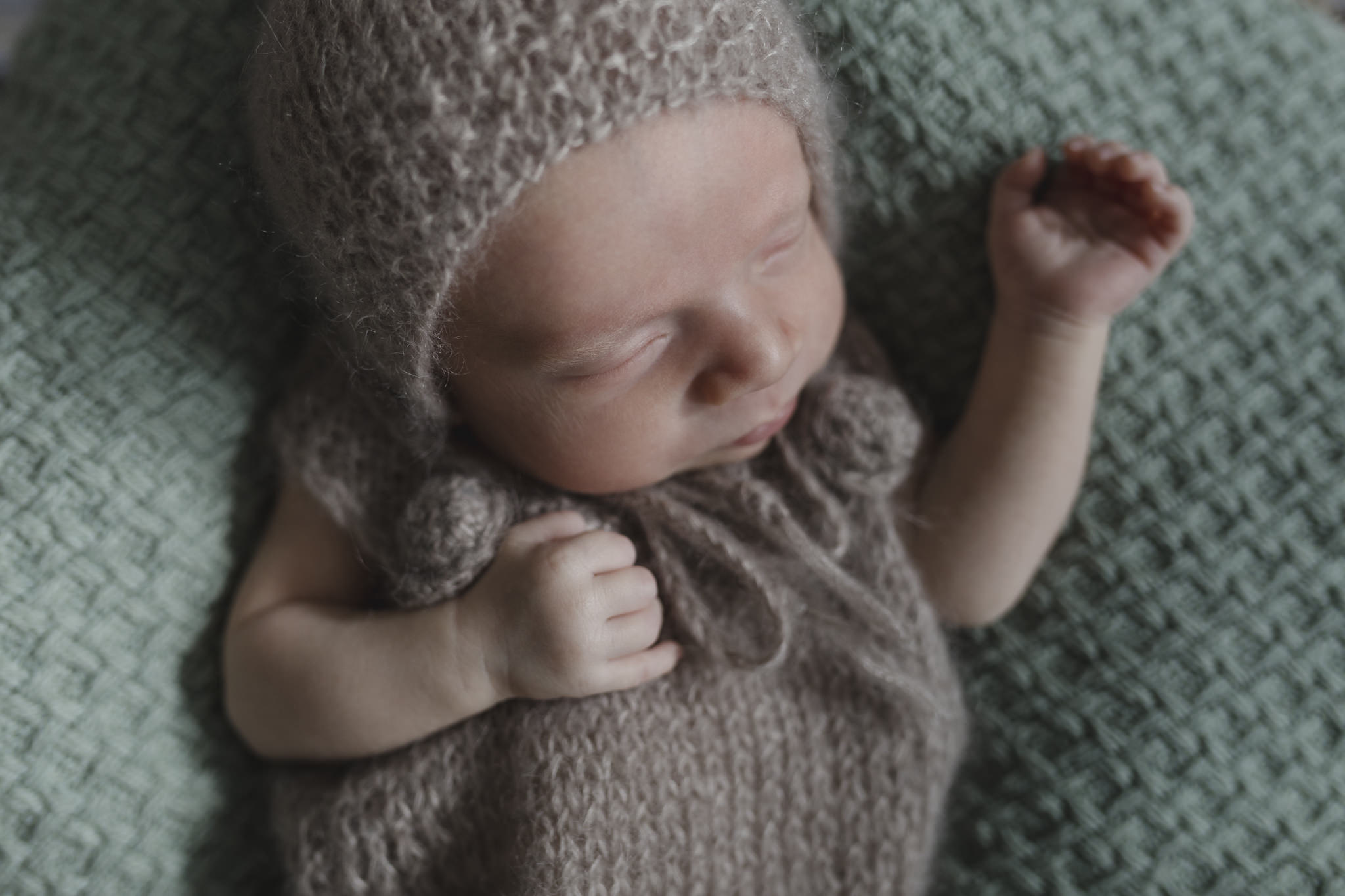 Babyfotograf Hamburg - Baby trägt braunen Strampler und schläft
