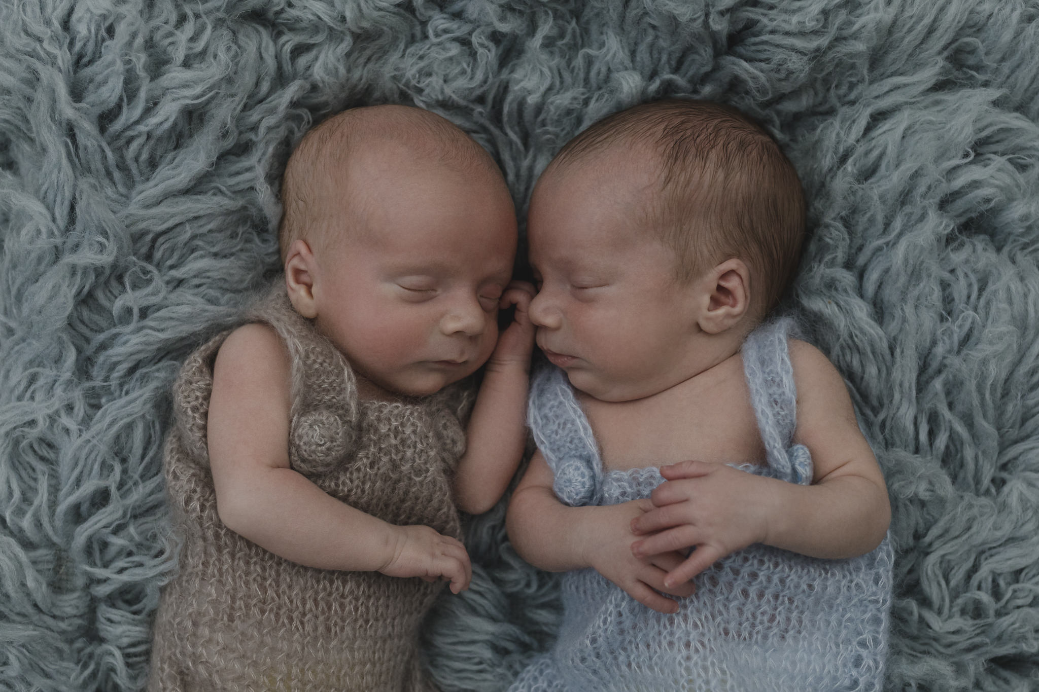 Babyfotograf Hamburg - Zwillinge liegen nebeneinander auf blauem Flokati