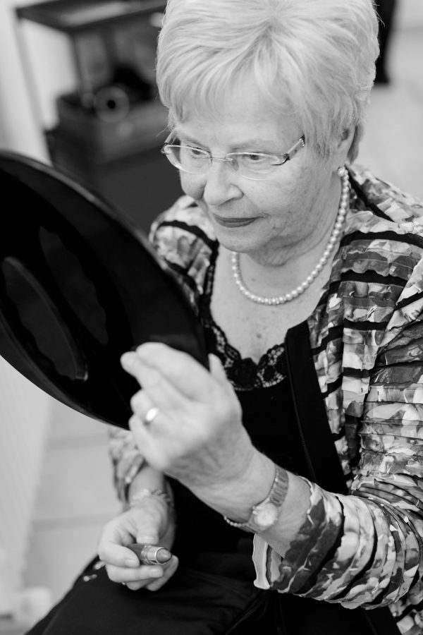 Oma schaut beim Styling prüfend in den Spiegel