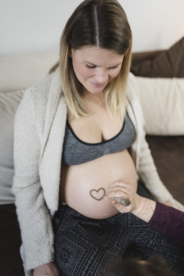 Babybauchfotografie Hamburg - das Henna Tattoo entsteht mit einem Herz als zentrales Element