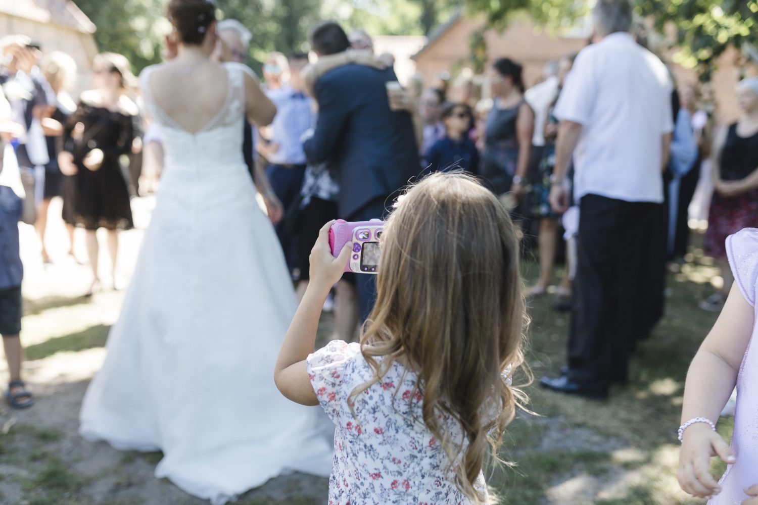 ein Kind macht mit seiner Kamera ein Foto der Braut