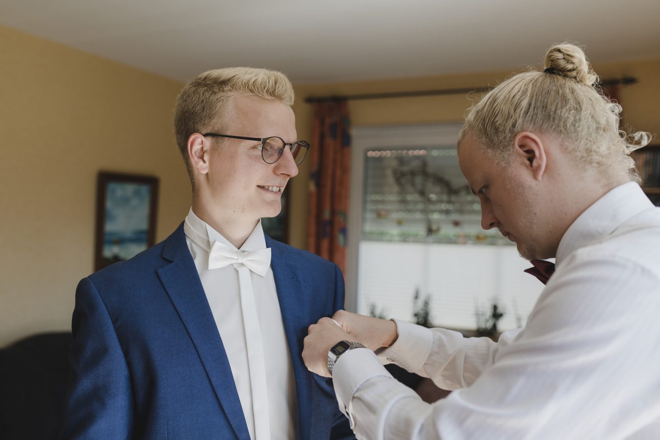 Getting Ready: der Trauzeuge steckt dem Bräutigam das Einstecktuch ins Jacket